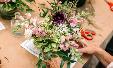 Photo of hands arranging a floral bouquet on a table