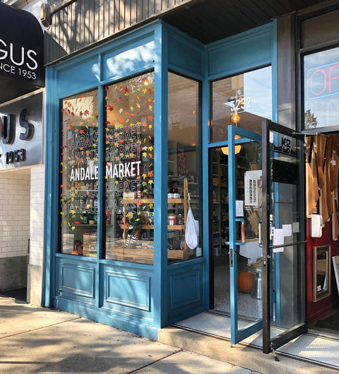 Blue storefront for Ándale Market with autumn-leaf window decorations, an open glass door, and the address 5232.