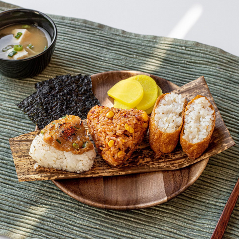 Japanese meal of onigiri rice balls and miso soup arranged on wooden dishes.