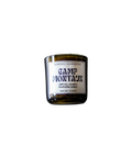 A Barnaby Black Burnwell Illuminaries Camp Montauk candle in an amber glass jar.