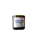 A Barnaby Black Burnwell Illuminaries Heirloom Tomato candle in an amber glass jar.