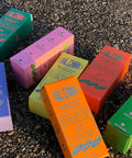 Several colorful boxes of Blomb perfume laid out randomly on asphalt.