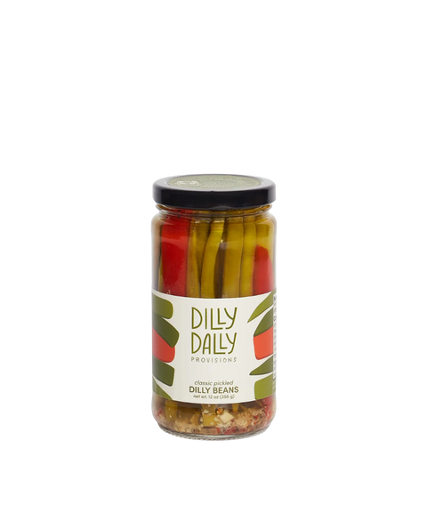 A glass jar of Dilly Dilly Provisions pickled dilly beans with a black lid.