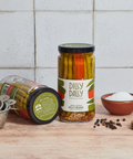 Two glass jars of Dilly Dally Provisions Dilly Beans on a wooden surface with a tiled background. 