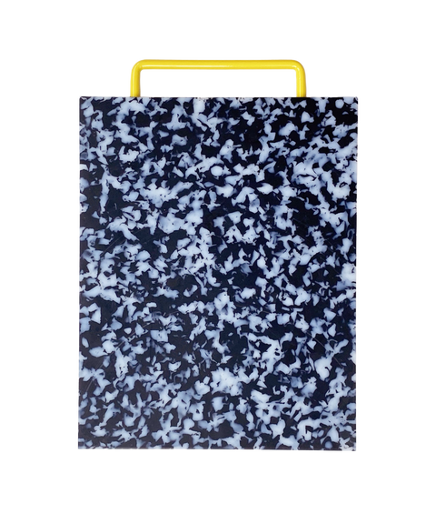 A rectangular plastic cutting board with a black and white marbled pattern and yellow metal handle, shown on a plain white background.