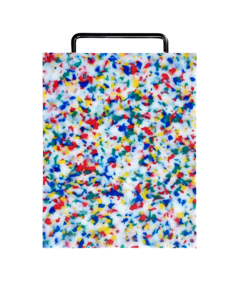 A rectangular plastic cutting board with a black metal handle, featuring a white base covered in dense multicolored confetti-like speckles in blue, red, yellow, and green, shown on a plain white background.