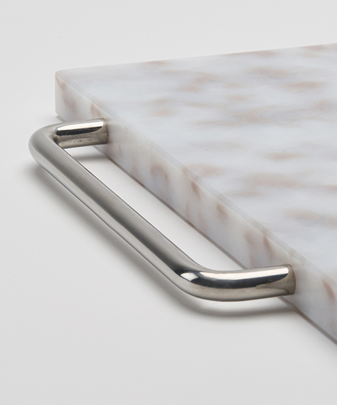 A close up of a rectangular plastic cutting board with a grey and white marbled pattern and silver chrome metal handle, shown on a plain white background.