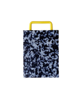A rectangular plastic cutting board with a black and white marbled pattern and yellow metal handle, shown on a plain white background.