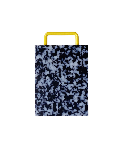 A rectangular plastic cutting board with a black and white marbled pattern and yellow metal handle, shown on a plain white background.