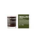 A Malin+Goetz Cannabis candle in a clear glass jar next to its dark green box.