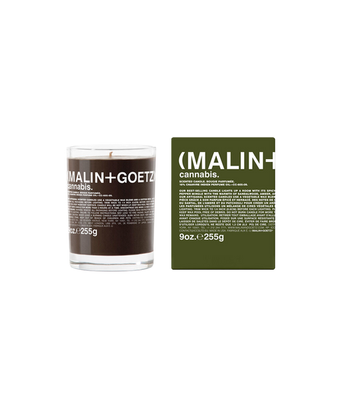 A Malin+Goetz Cannabis candle in a clear glass jar next to its dark green box.