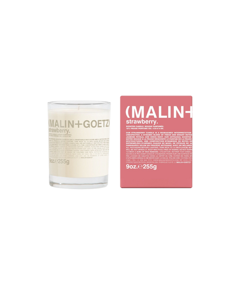 A Malin+Goetz Strawberry candle in a clear glass jar next to its pink box.