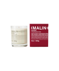 A Malin+Goetz Tomato candle in a clear glass jar next to its dark red box.