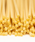 Close-up of uncooked bucatini pasta on a white background.