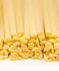 Close-up of uncooked linguine pasta on a white background.