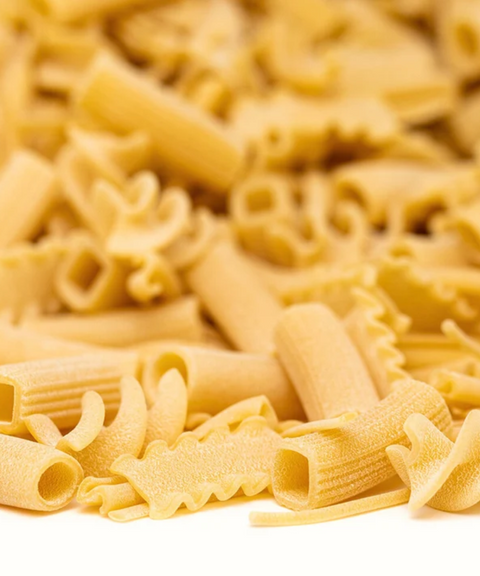 Close-up of uncooked mixed pasta shapes on a white background.