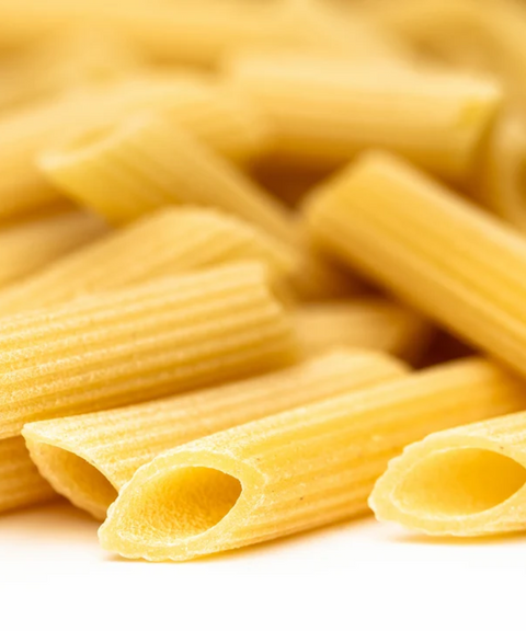 Close-up of uncooked penne pasta tubes on a white background.