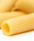 Close-up of uncooked rigatoni pasta tubes on a white background.