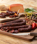 Palacios chorizo on a wooden serving boards with sliced pieces, cheese, olives, and bread.