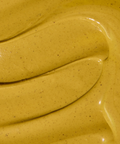 Close-up of a glossy yellow-green pistachio spread with dark specks and curved swirls.
