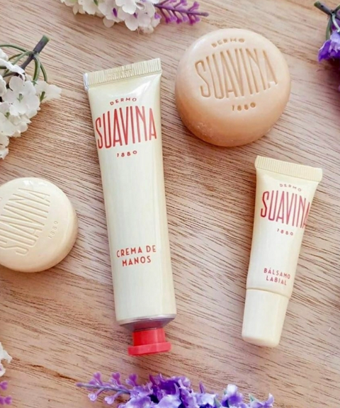 Three Suavina skincare products arranged on a light wood surface with small white and purple flowers.