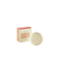 A round cream-colored pot of Suavina original lip balm next to its coral and cream packaging box.